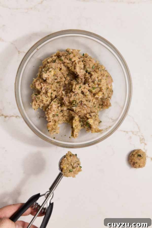 Lemon Caper Chicken Meatballs 7 Ground chicken mixture being scooped into meatballs with a cookie scoop.