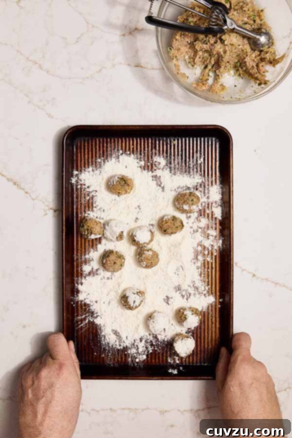 Lemon Caper Chicken Meatballs 8 Chicken meatballs being rolled in flour on a tray for pan-frying.
