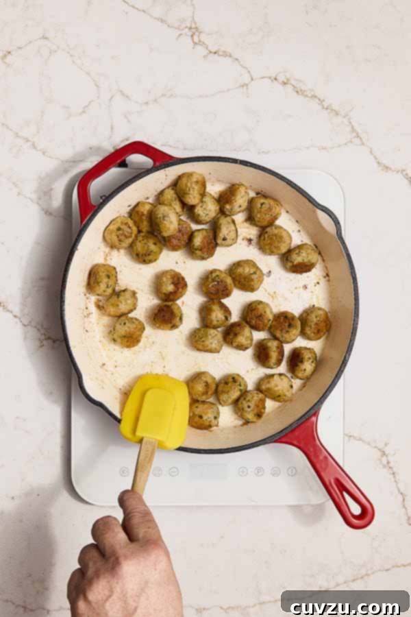 Lemon Caper Chicken Meatballs 9 Chicken meatballs browning in a skillet to develop a golden crust.