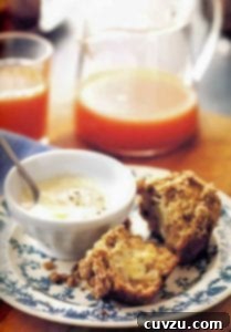 A cut streusel-topped date muffin slathered with butter on a decorative plate
