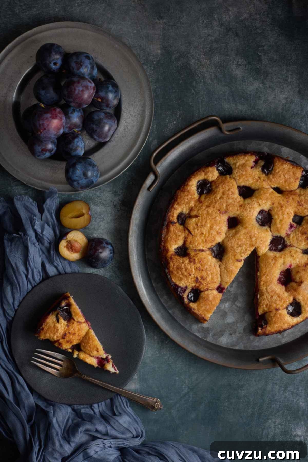 Golden Plum Torte 12 An inviting overhead view of a whole, freshly baked plum torte, with one delicious slice carefully removed and served on a plate, ready to be enjoyed.