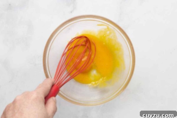 Tropical Coconut Dream Pie 13 A man's hand whisking egg yolks in a bowl.