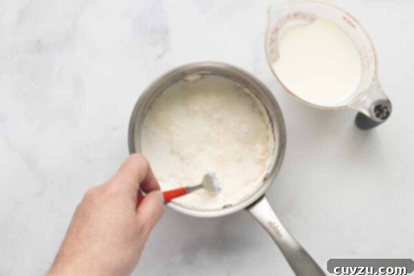 Tropical Coconut Dream Pie 15 A man's hand mixing flour, salt, sugar, and milk in a saucepan.