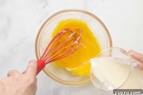 Tropical Coconut Dream Pie 16 A man's hand whisking hot milk into egg yolks.