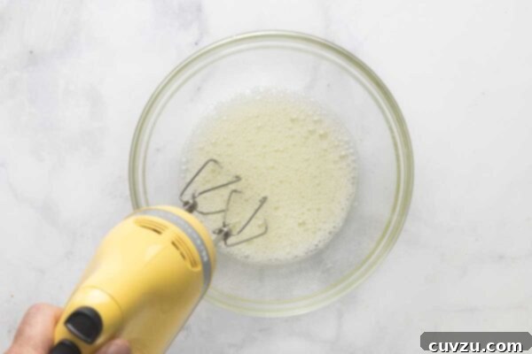 Tropical Coconut Dream Pie 20 A handheld mixer beating egg whites.