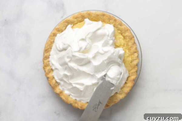 Tropical Coconut Dream Pie 22 A coconut cream pie with meringue being slathered on it.