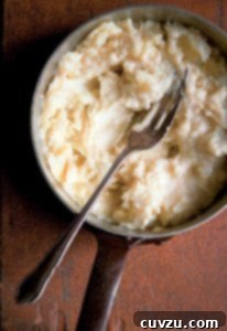 Rustic Fork-Mashed Potatoes 4 A pot of fork-mashed potatoes with a fork resting inside.