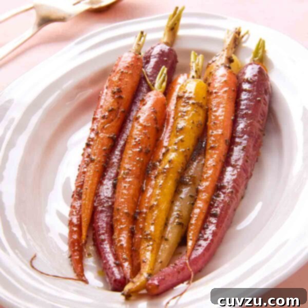 A dish of vibrant, colorful braised carrots with an orange-rosemary glaze on a white platter.