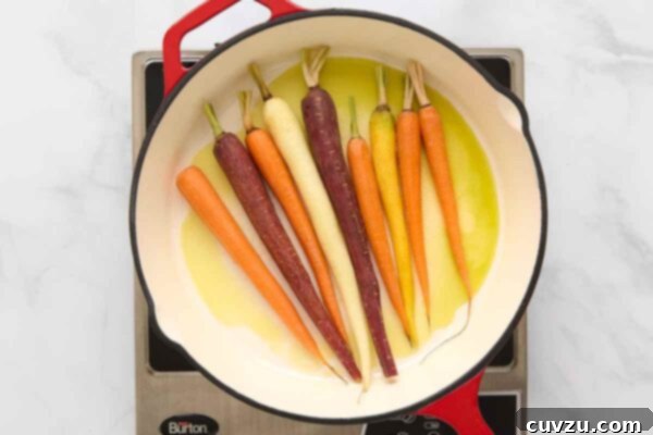 Carrots lightly sautéing in olive oil and melted butter in a skillet, beginning to turn golden.