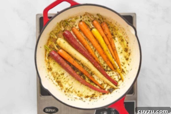 Braised carrots in a skillet, coated in a buttery rosemary and orange glaze.