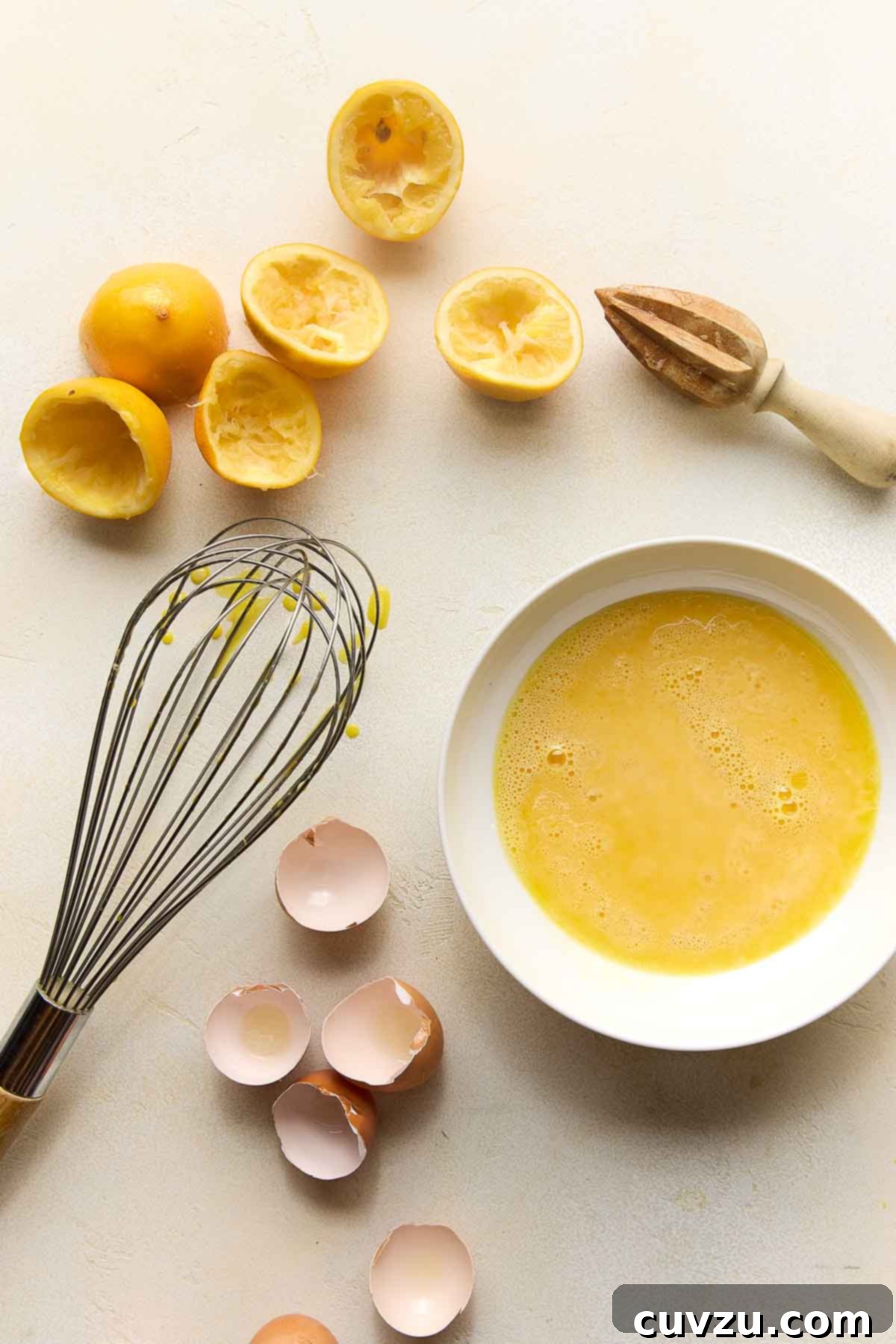 Meyer Lemon Curd: Zesty Citrus Delight 11 A bowl of uncooked Meyer lemon curd mixture, surrounded by egg shells, juiced lemon halves, and a whisk – capturing the essence of the preparation process.