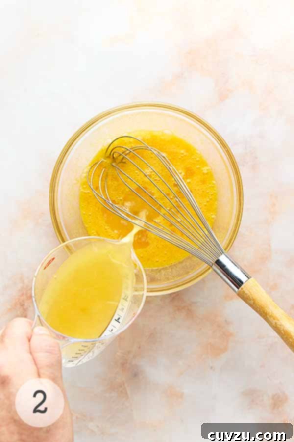 Meyer Lemon Curd: Zesty Citrus Delight 6 Lemon juice being poured into a bowl of Meyer lemon curd base, ready to be incorporated.