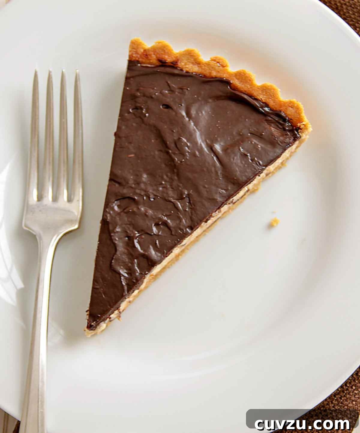 Rich Chocolate Peanut Butter Cloud Tart 2 A beautifully presented slice of chocolate peanut butter tart, showcasing its distinct layers: a golden cookie crust, a creamy peanut butter mousse filling, and a decadent chocolate ganache topping. Perfect for any special occasion.