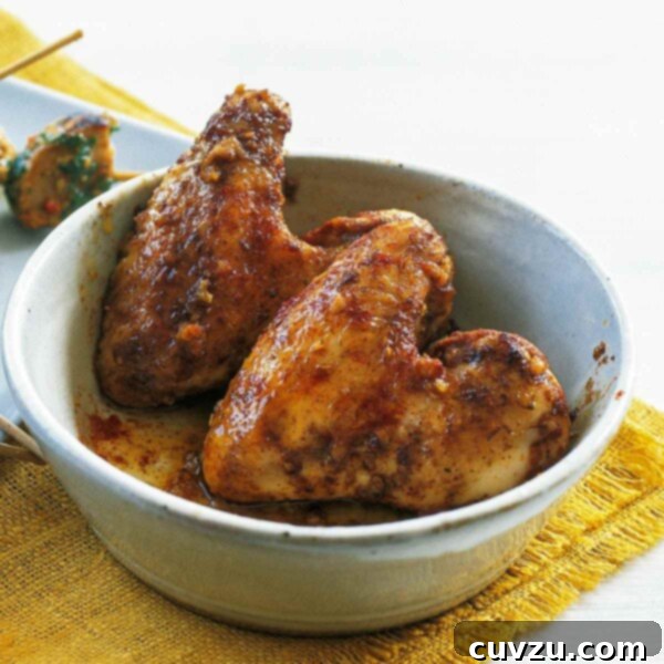 A white bowl with two chicken wings with garlic and paprika on a yellow placemat.