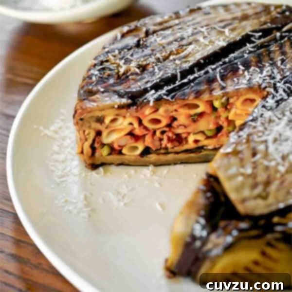 A slice of Eggplant Timbale on a plate, revealing the pasta, meat, and cheese filling.