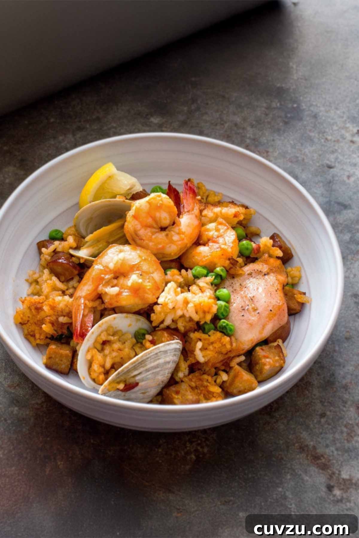 Golden Saffron Paella 2 A vibrant bowl of Spanish paella, generously filled with saffron-infused rice, succulent shrimp, tender mussels, savory chorizo, seasoned chicken, and bright green peas.