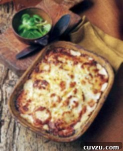 Casserole dish of root vegetable gratin topped with bubbly brown cheese on wood table