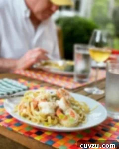 Leek and Shrimp Pasta Delight 4 A white plate filled with shrimp and leek pasta on a multi-colored woven placemat, representing a classic recipe.