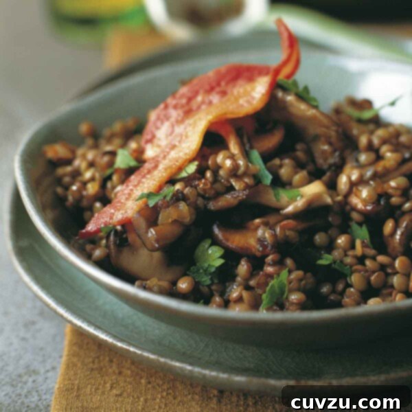 A close-up shot of sautéed bacon, mushrooms, and lentils in a bowl.