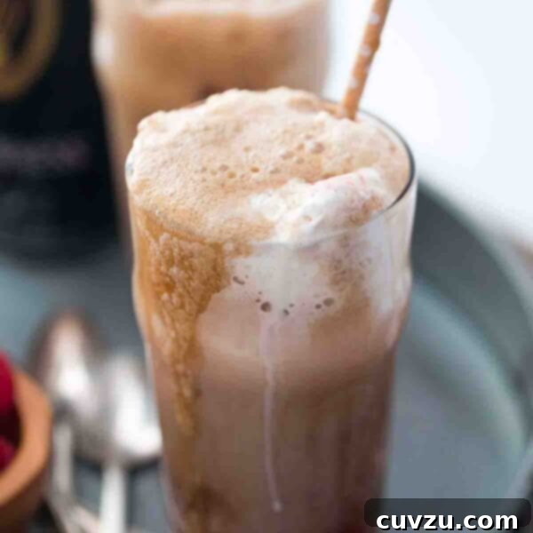 Two Guinness floats garnished with chocolate shavings, served in tall glasses with straws on a metal tray.