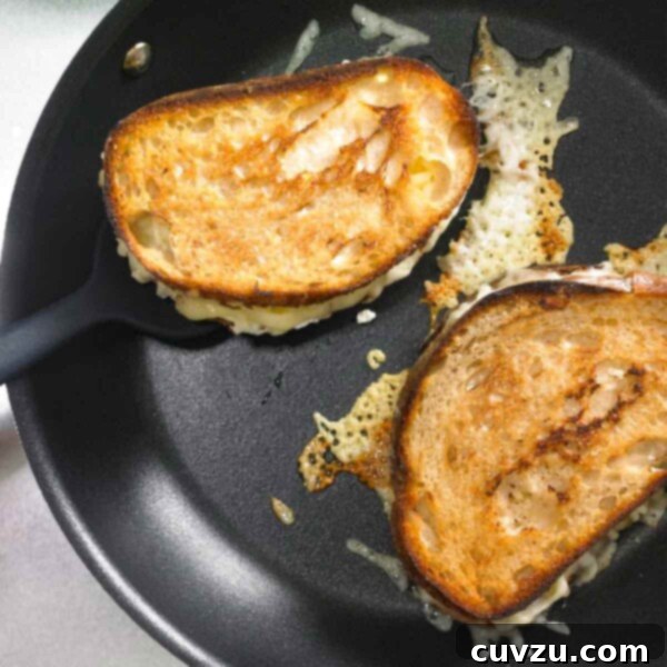 Two Hog Island grilled cheese sandwiches in a skillet with some cheese melting from them.