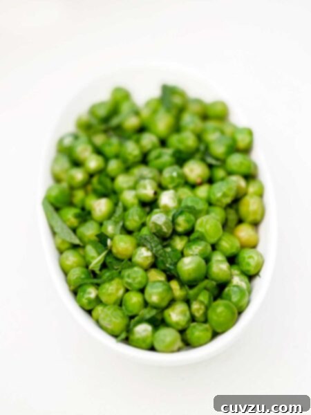 White bowl of fresh peas with mint, a vibrant and refreshing side dish.