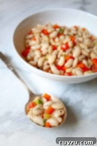 A close-up of tender Tuscan white beans in a ceramic bowl, garnished with fresh herbs, ready to be enjoyed.