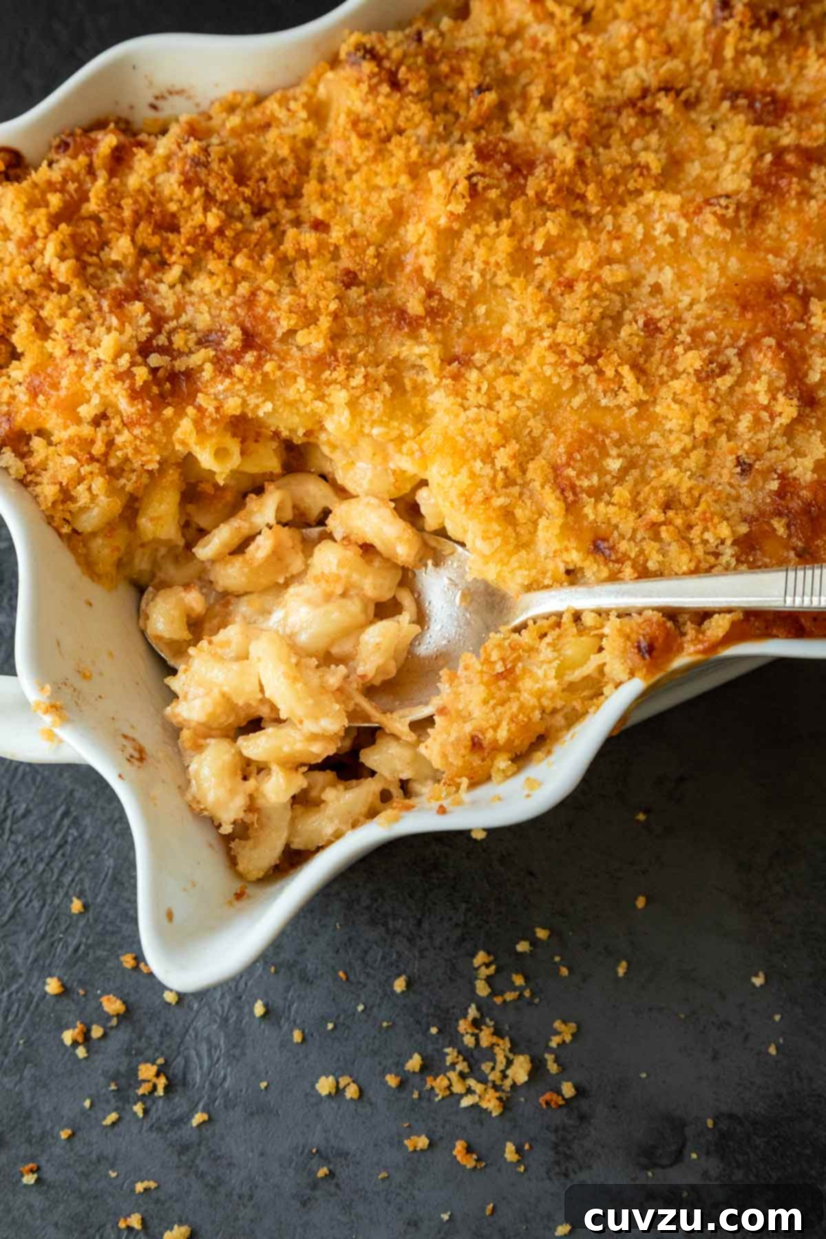 A casserole dish of macaroni and cheese with a spoon inside.