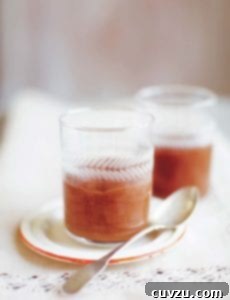 Two individual servings of chocolate mousse in glass tumblers, served on a small plate with a silver spoon.