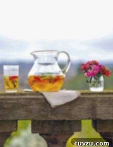 A pitcher of Pimm's cup, with a half-filled glass and a vase of flowers on either side of it.