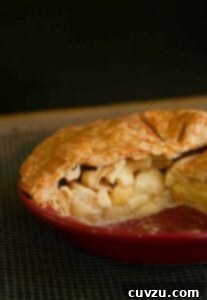 An apple pie with a Cheddar crust in a red pie pan cut into to show the Golden Delicious apples inside.