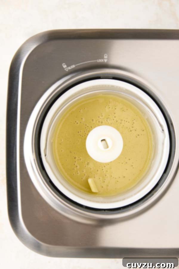 Authentic Italian Creamy Pistachio Gelato 11 The chilled, light green pistachio gelato base being poured into the canister of an ice cream maker, ready for churning.