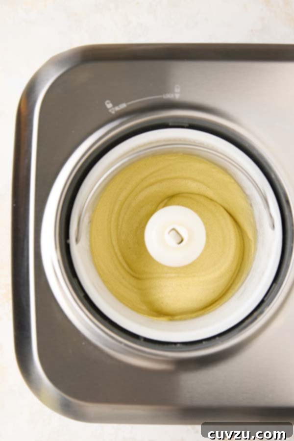 Authentic Italian Creamy Pistachio Gelato 12 Thick and creamy pistachio gelato churning actively in the ice cream maker, nearing its soft-serve consistency.
