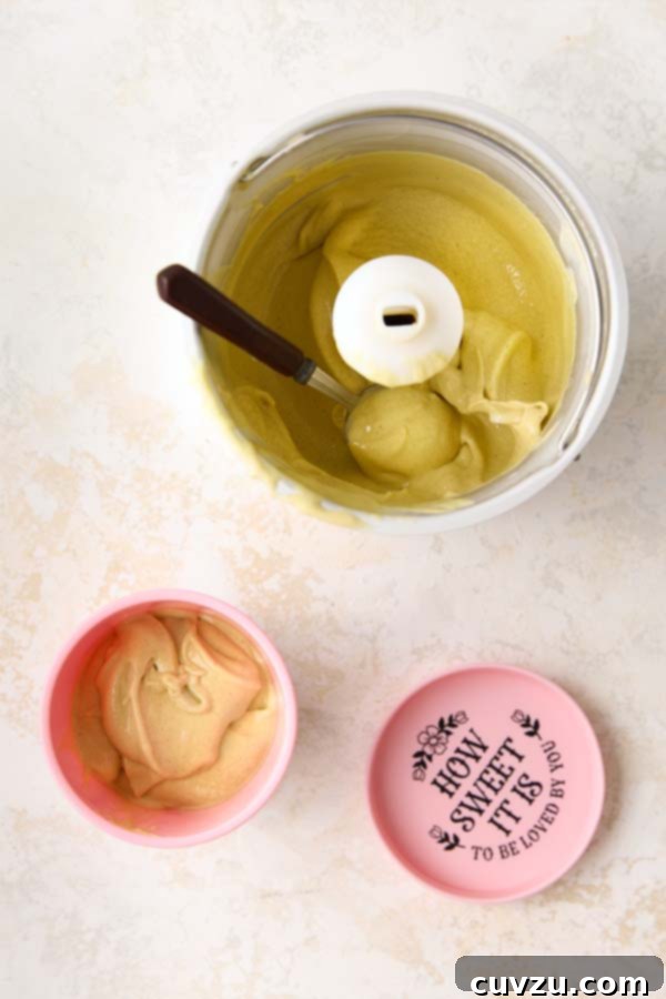 Authentic Italian Creamy Pistachio Gelato 13 Scooping freshly churned pistachio gelato from the ice cream maker into a pink storage container, indicating the final step before freezing.