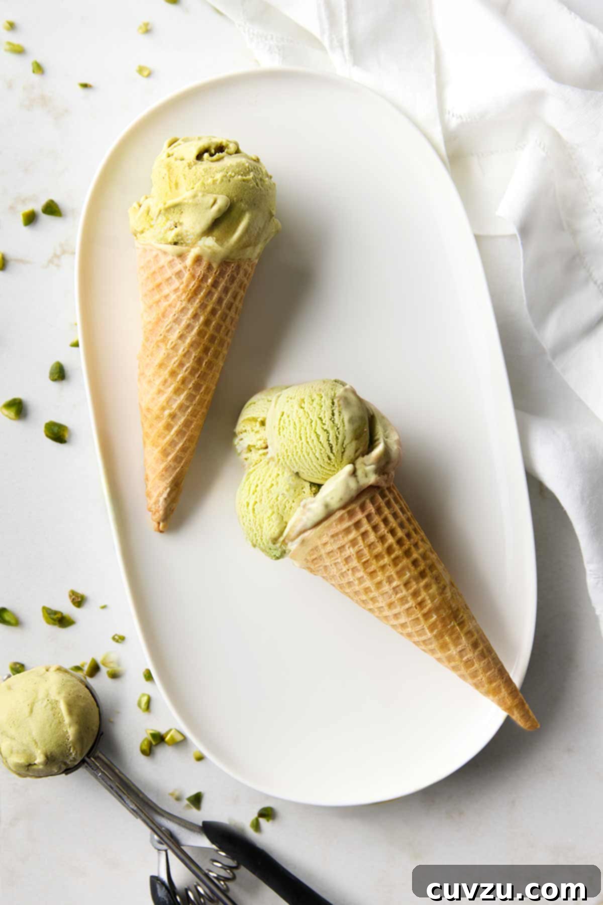 Authentic Italian Creamy Pistachio Gelato 14 A platter featuring two elegant ice cream cones generously filled with creamy pistachio gelato, perfectly ready to be savored.