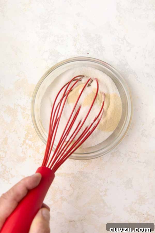 Authentic Italian Creamy Pistachio Gelato 6 A red whisk combines granulated sugar and a xanthan gum in a small glass bowl, preparing the dry ingredients.
