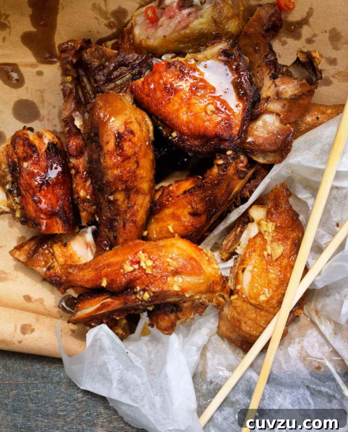 Momofuku fried chicken pieces on a piece of brown paper, covered with Octo Vin, with chopsticks piled beside.