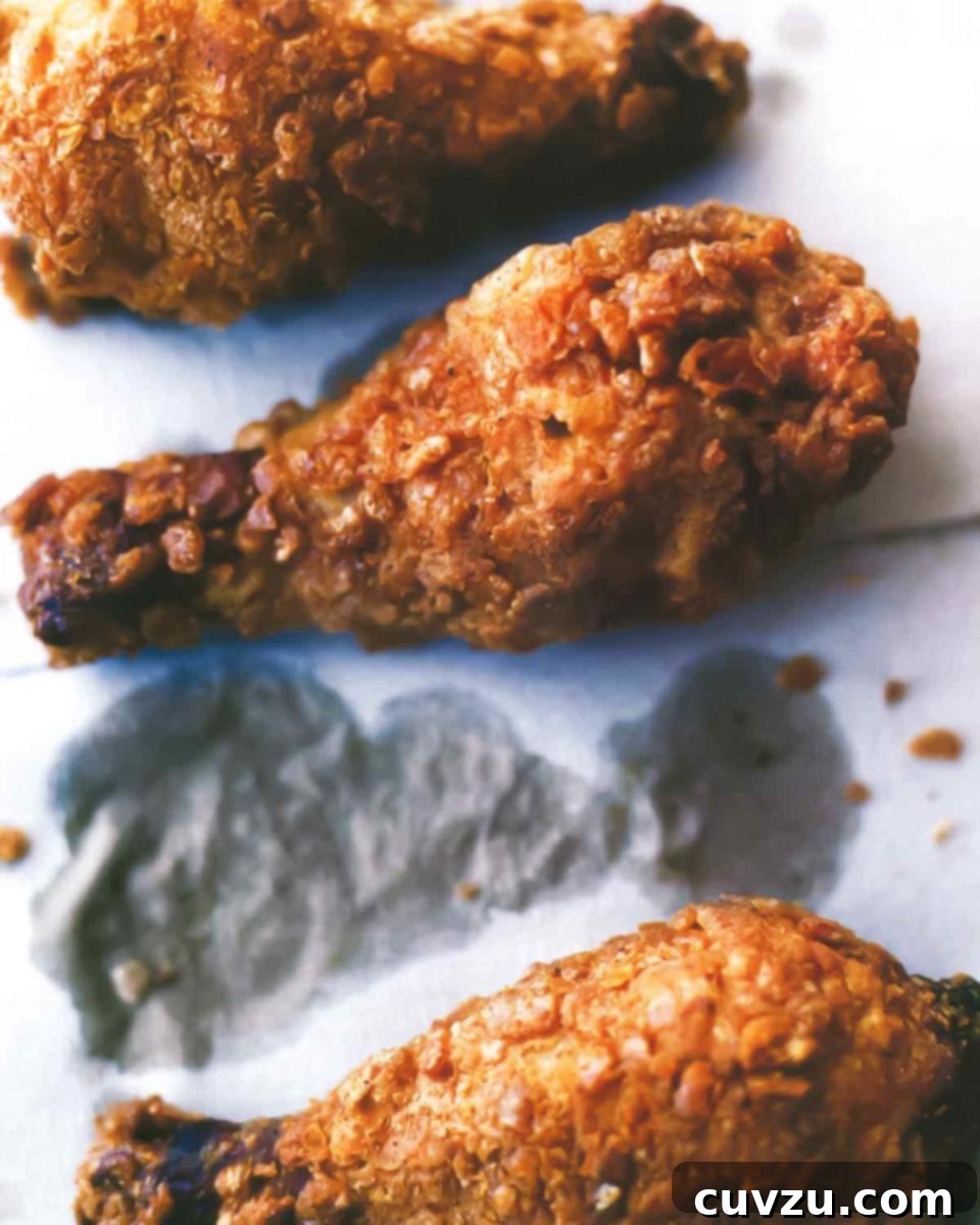 Crispy fried chicken pieces on grease-stained paper, showcasing the unique cereal and cracker coating.