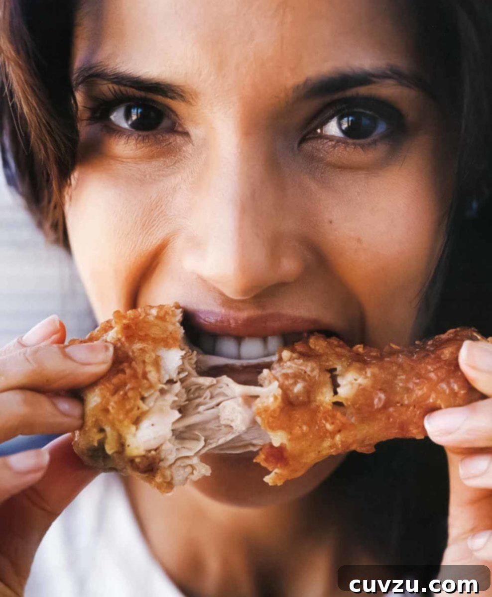 Padma Lakshmi enjoying a piece of her signature crispy fried chicken.