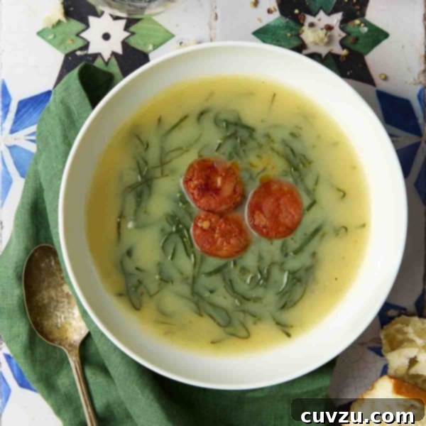 Caldo Verde: Portugal's Iconic Green Soup 13 A white bowl of Caldo Verde, or Portuguese kale soup (green broth) with thinly sliced kale and three chouriço coins floating in the center.