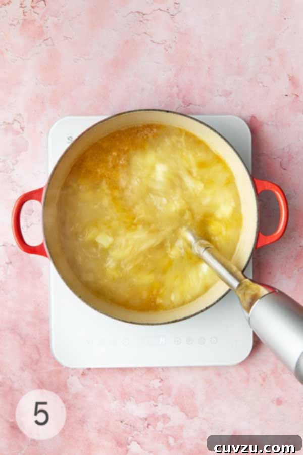 Caldo Verde: Portugal's Iconic Green Soup 10 A wand blender pureeing the potato and broth base for Portuguese green broth soup—Caldo Verde—directly in the pot.