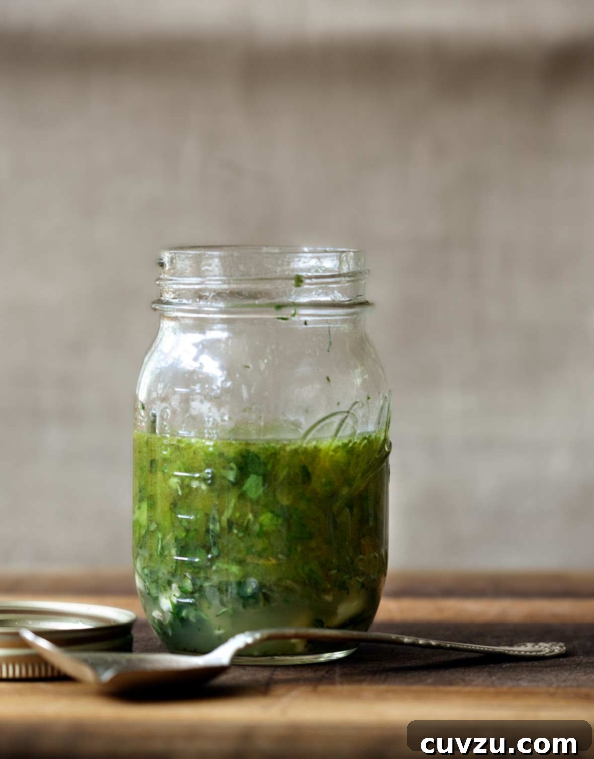 Zesty Hellenic Marinade 2 Mason jar of Greek marinade with parsley, oregano, thyme, rosemary, basil on a cutting board