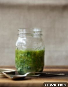 Mason jar of Greek marinade with parsley, oregano, thyme, rosemary, basil on a cutting board