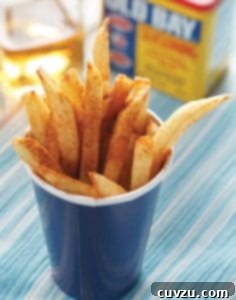 A blue paper cup filled with beach fries that are sprinkled with Old Bay seasoning.