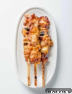 A white oval serving platter topped with three skewers of chicken yakitori with honey sauce.