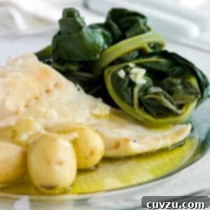 A white plate of bacalhau consoada or Portuguese Christmas Eve cod, with salt cod, small potatoes, and blanched kale.