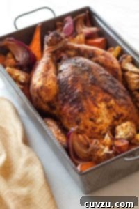 A deep roasting pan filled with roast chicken and vegetables.