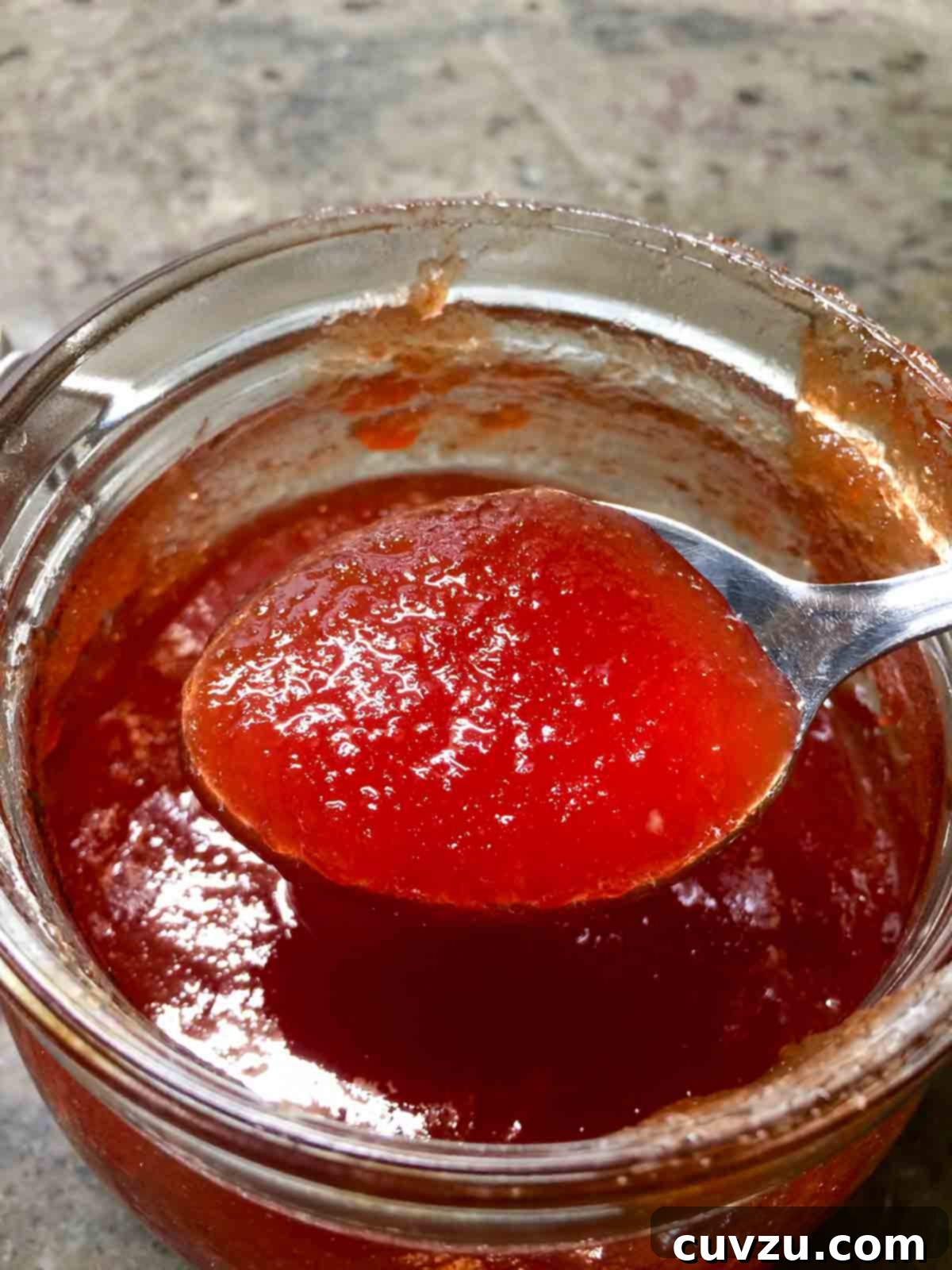 Vibrant Portuguese Tomato Jelly 5 A jar of Portuguese tomato jelly with a filled spoon above it.
