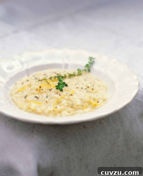 A white bowl filled with lemon and thyme risotto and topped with a sprig of thyme and some lemon zest