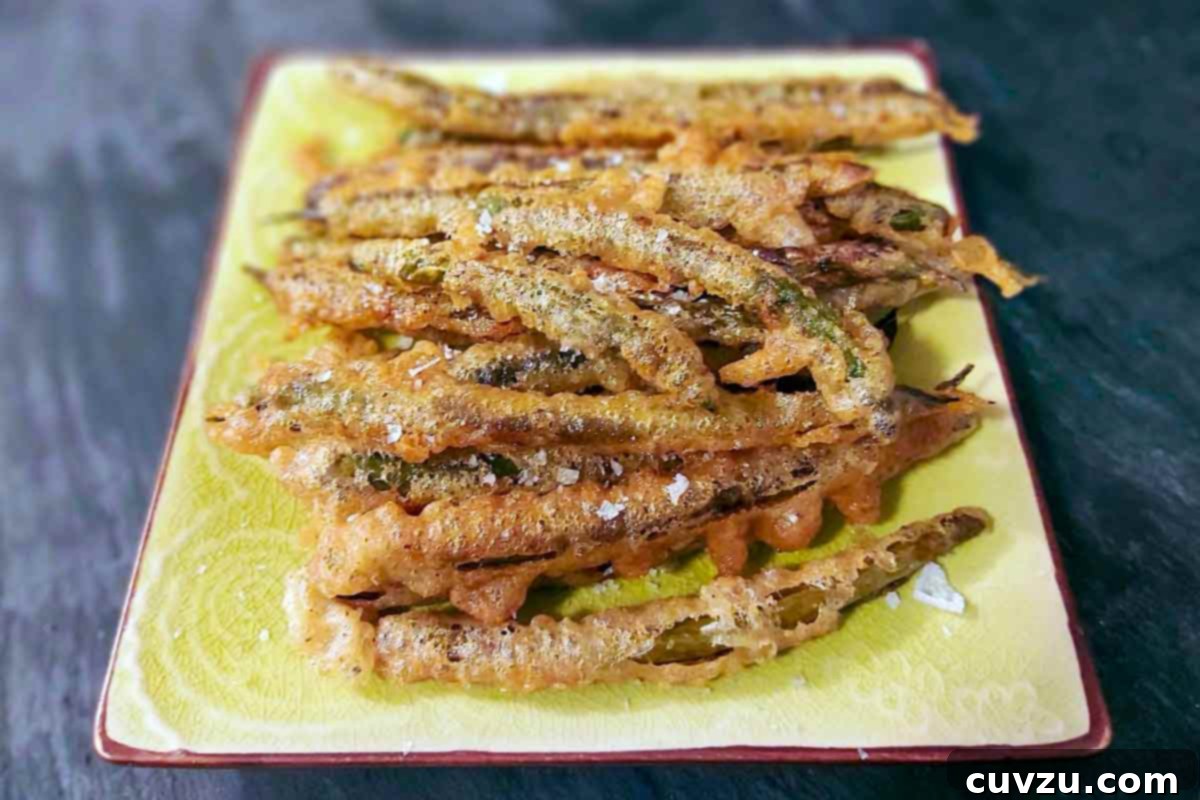 Crispy Portuguese Green Bean Fritters 3 Portuguese deep-fried green beans piled high on a rectangular platter, generously sprinkled with flaky salt, invitingly ready to be eaten.